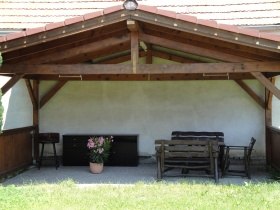 &Uuml;berdachte Terrasse mit Holzb&auml;nken und einem Blumentopf.