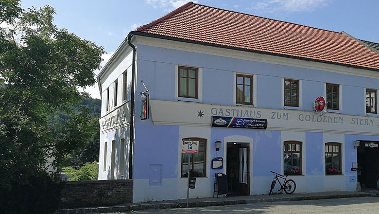 Ein zweist&ouml;ckiges Geb&auml;ude mit der Aufschrift 'Gasthaus zum Goldenen Stern' und einem Fahrrad davor.