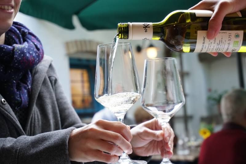Wein wird in ein Glas gegossen, während eine Person es hält.