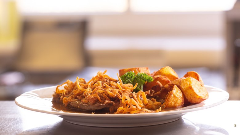 Ein Teller mit Zwiebelrostbraten, Röstzwiebeln und Bratkartoffeln.