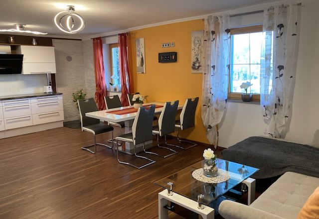 Moderne Wohnk&uuml;che mit Esstisch, St&uuml;hlen, Sofa und K&uuml;chenzeile.