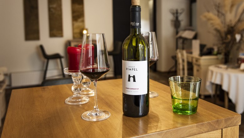 Weingl&auml;ser mit Rotwein und Weinflasche im Verkostungsraum des Weinguts