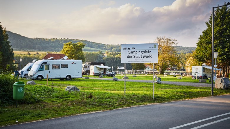 Campingplatz in Melk mit Wohnmobilen und einem Schild im Vordergrund.