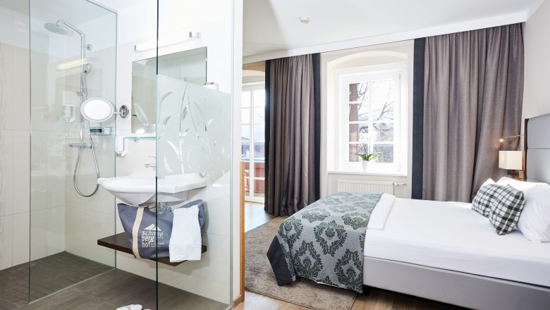 Modernes Hotelzimmer mit Doppelbett und Glasdusche.