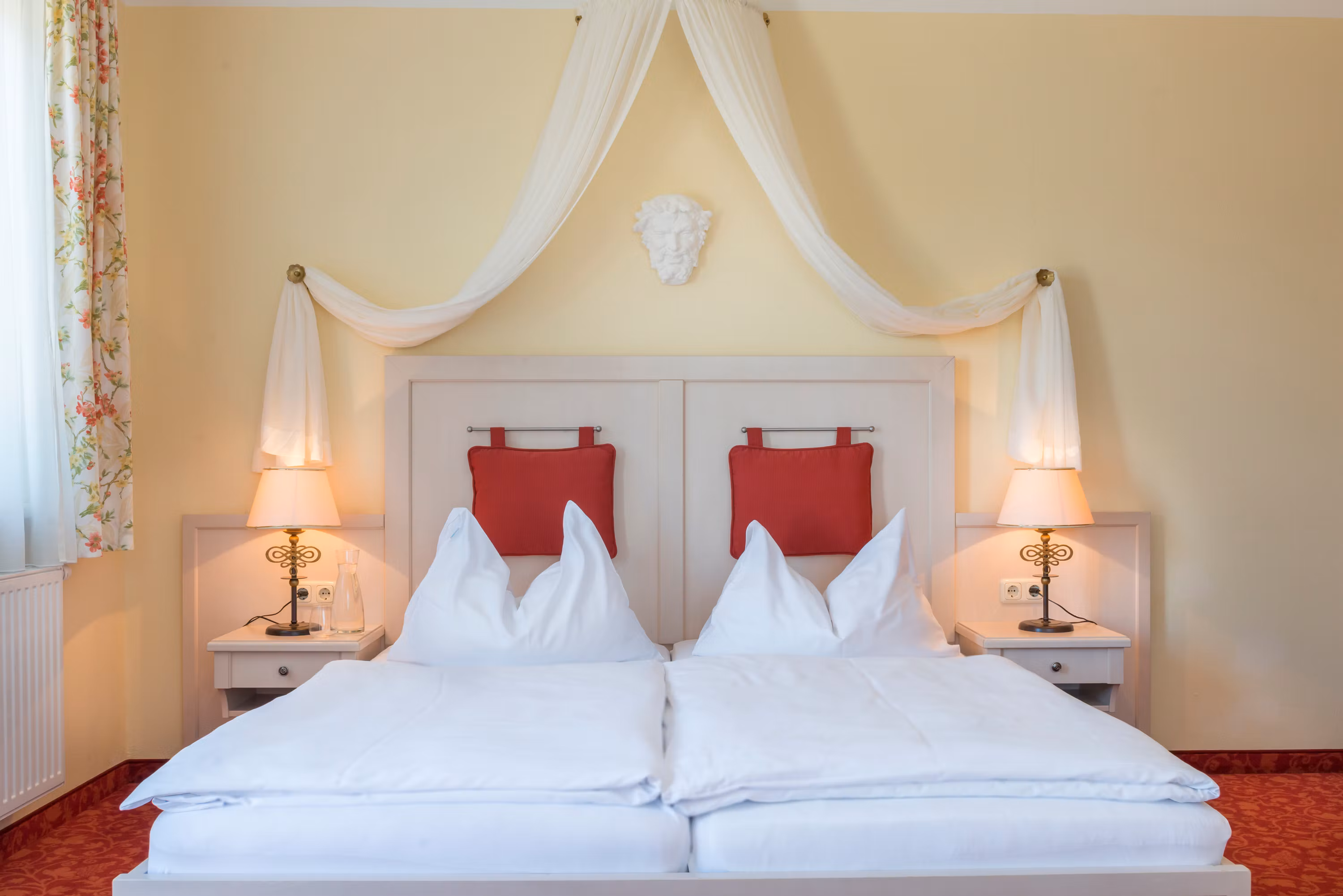 Zimmeransicht mit Himmelbett und roten Polstern