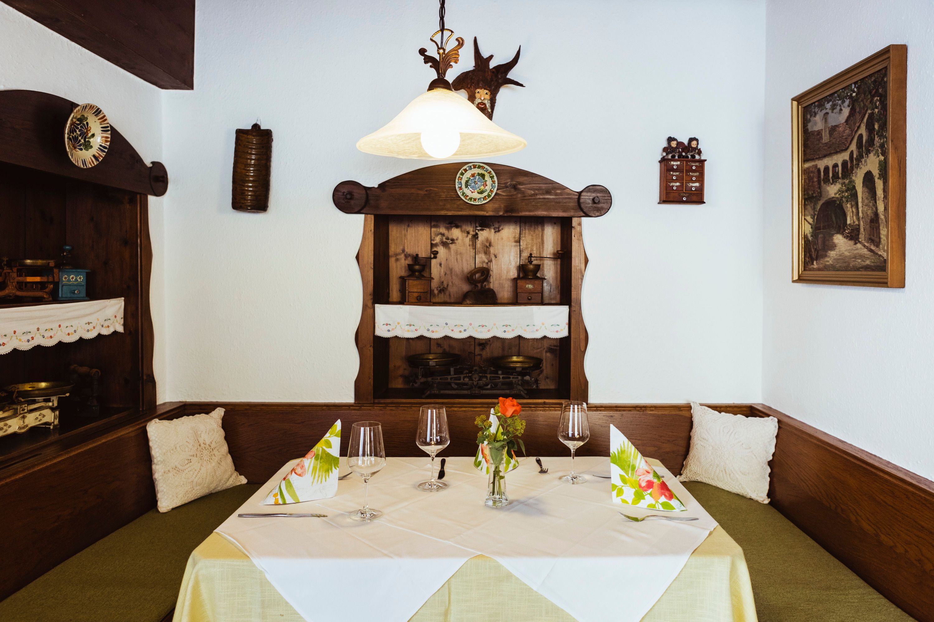 Gemütliche Sitzecke in einem Restaurant mit Holzmöbeln, dekorativen Details und gedecktem Tisch.