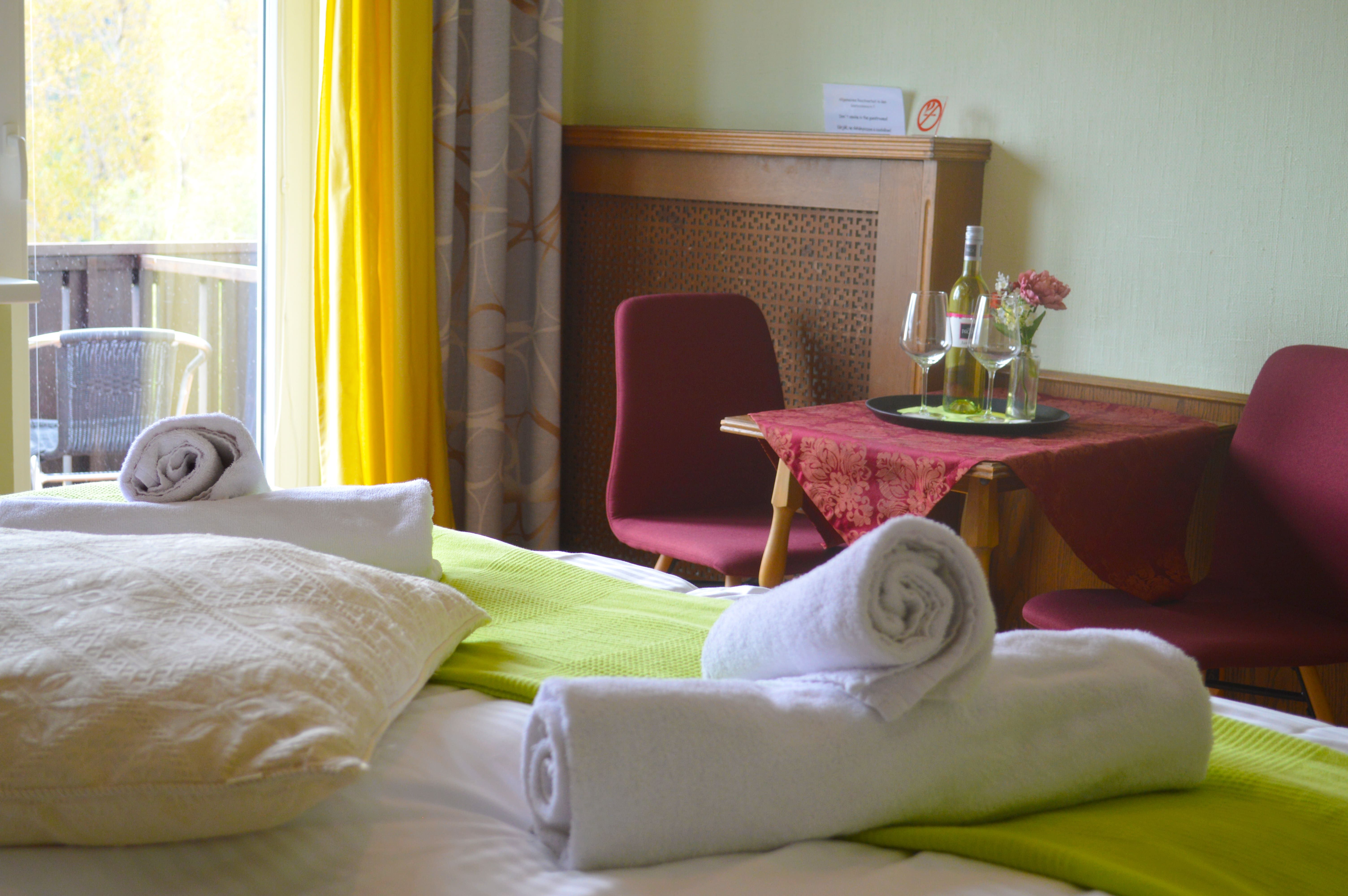 Doppelzimmer mit Bett, Tisch, Stühlen und Balkon.