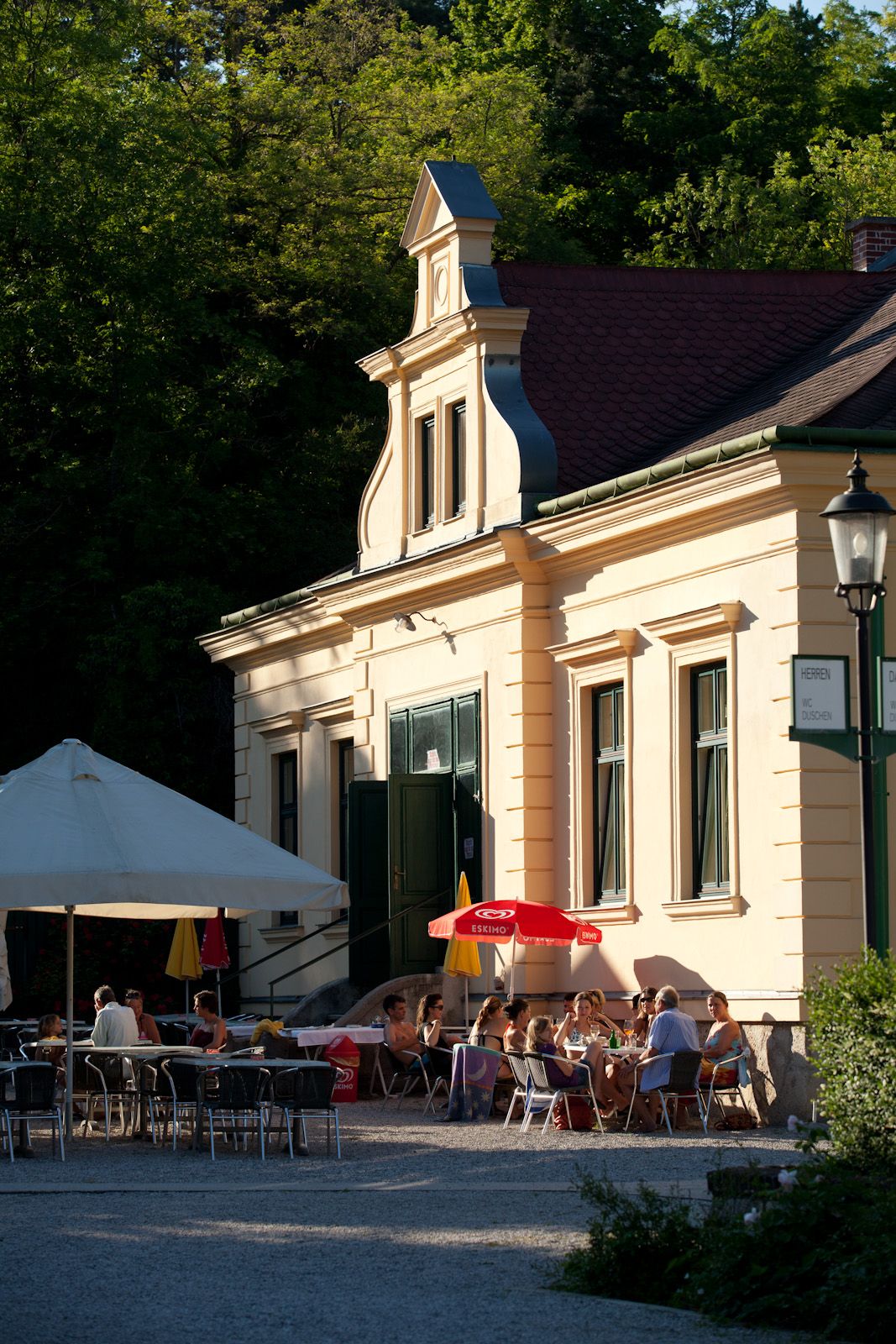 Außenansicht eines Restaurants mit Sonnenschirmen und Gästen im Freien.