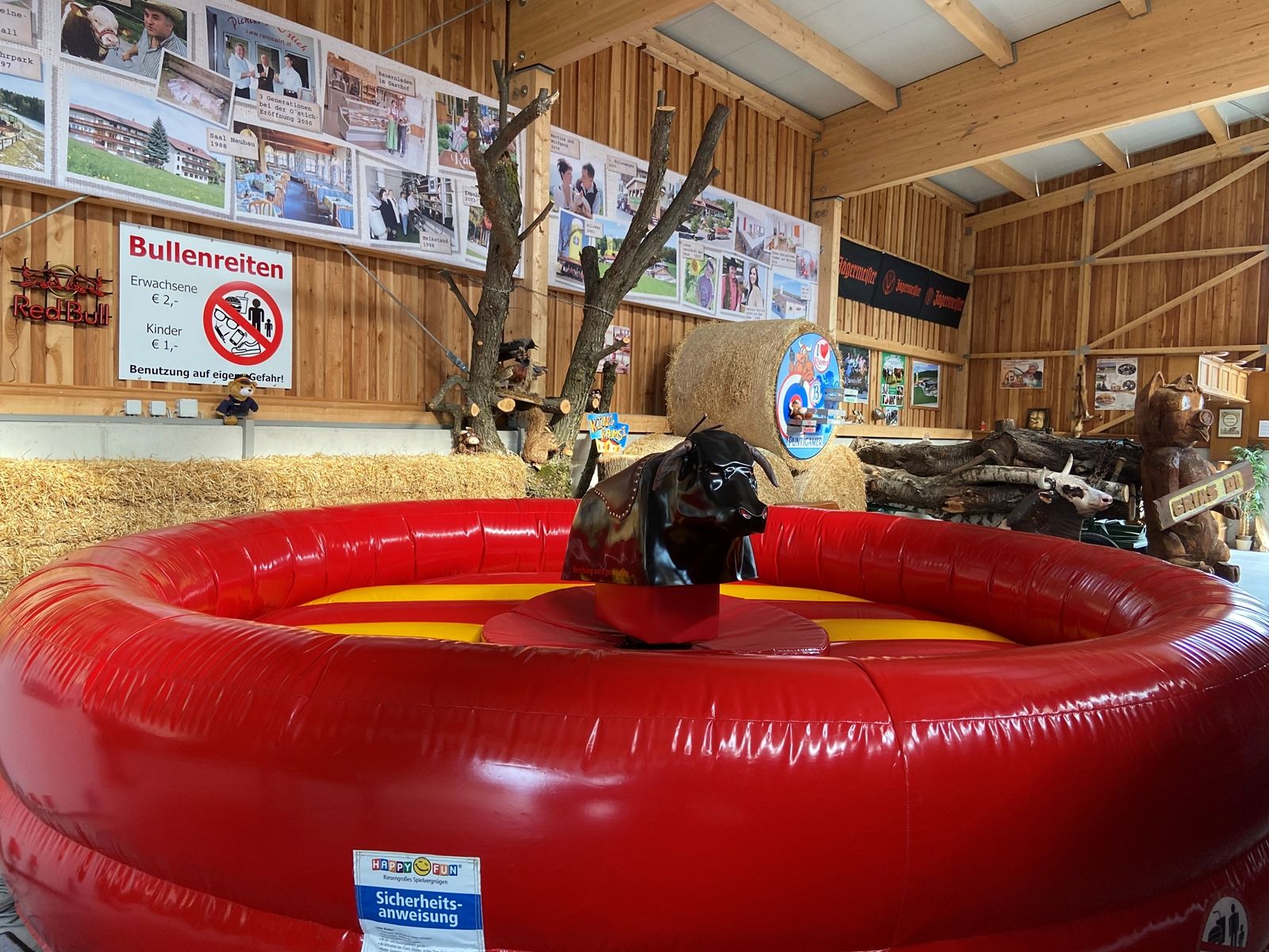 Aufblasbare Bullenreit-Anlage in einer Holzhütte mit Dekorationen und Schildern.