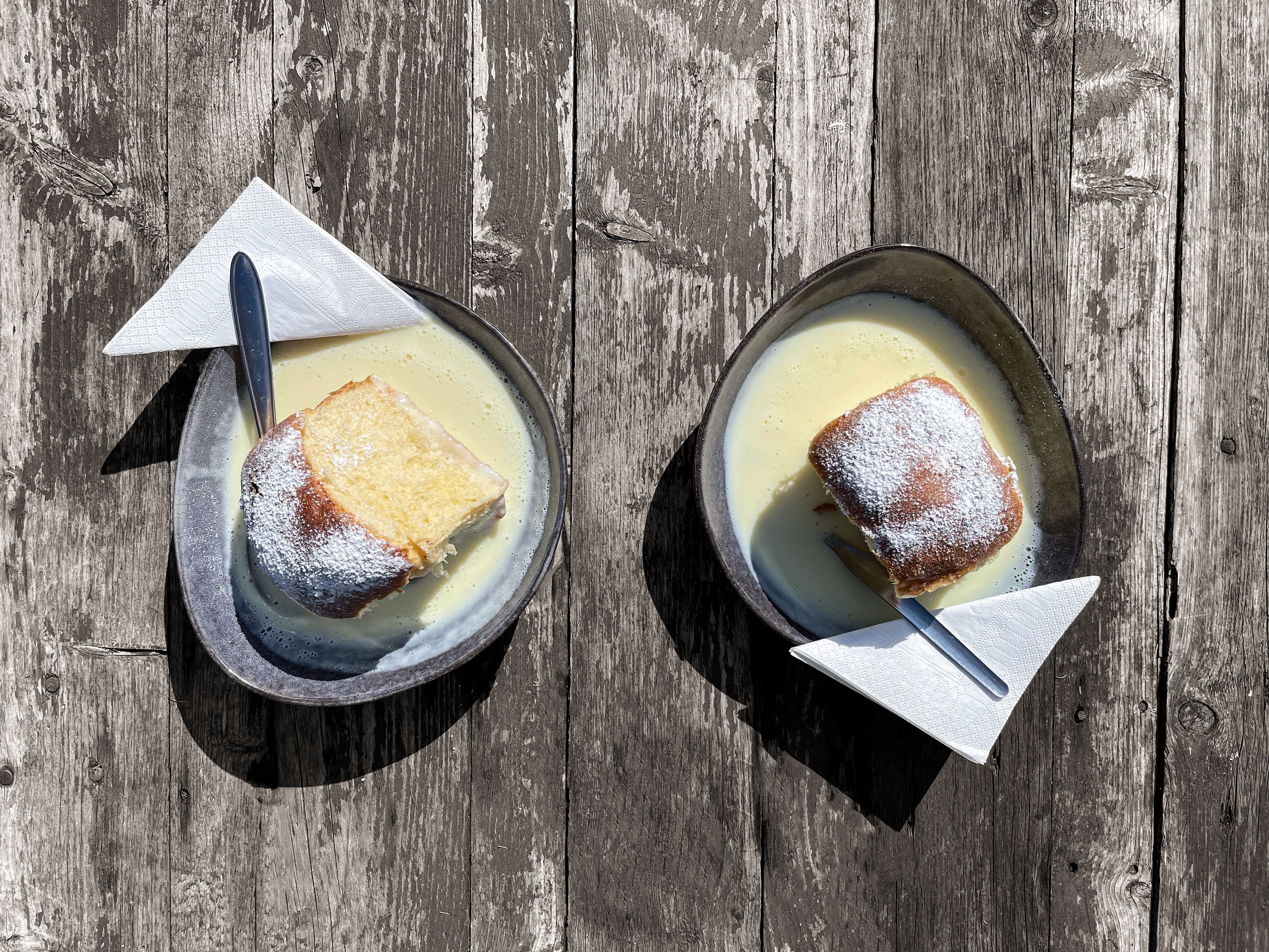 Menschen an einer Haltestelle mit Zug und Holzgebäude.