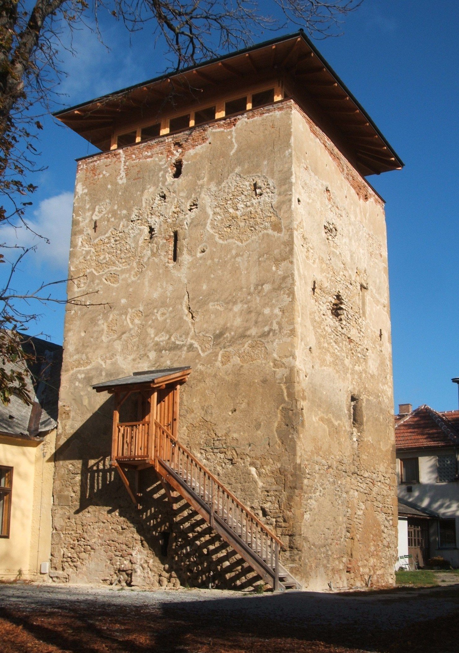 Ein alter Wehrturm mit bröckelnder Fassade und einer Holztreppe an der Seite.