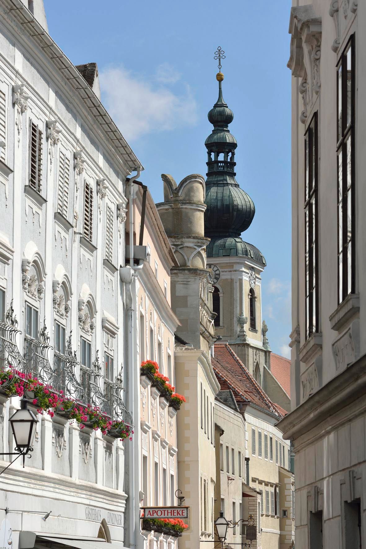 Straßenszene mit historischen Gebäuden und Kirchturm im Hintergrund.