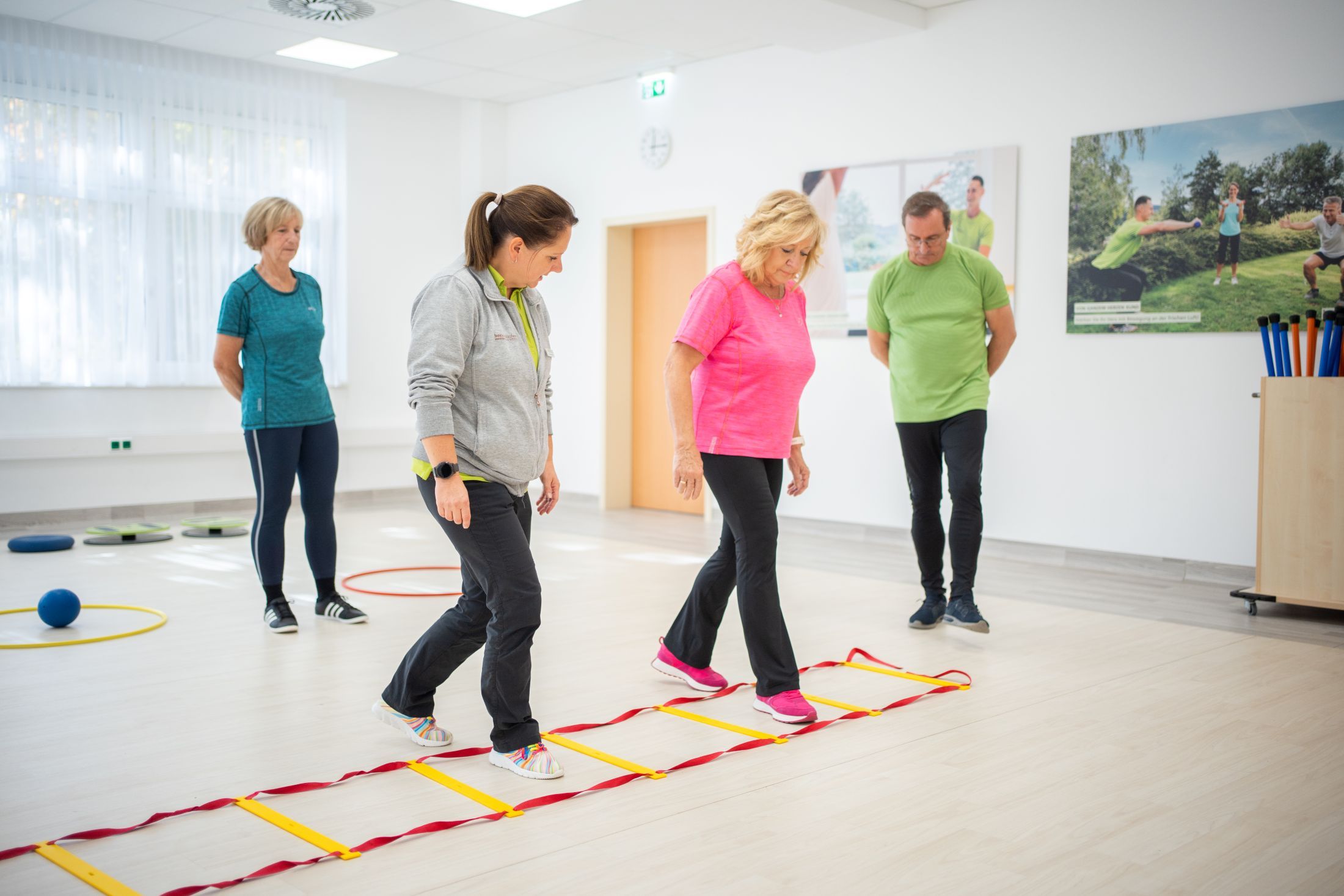 Personen in einem Fitnessstudio, die eine Übung mit einer Koordinationsleiter machen.