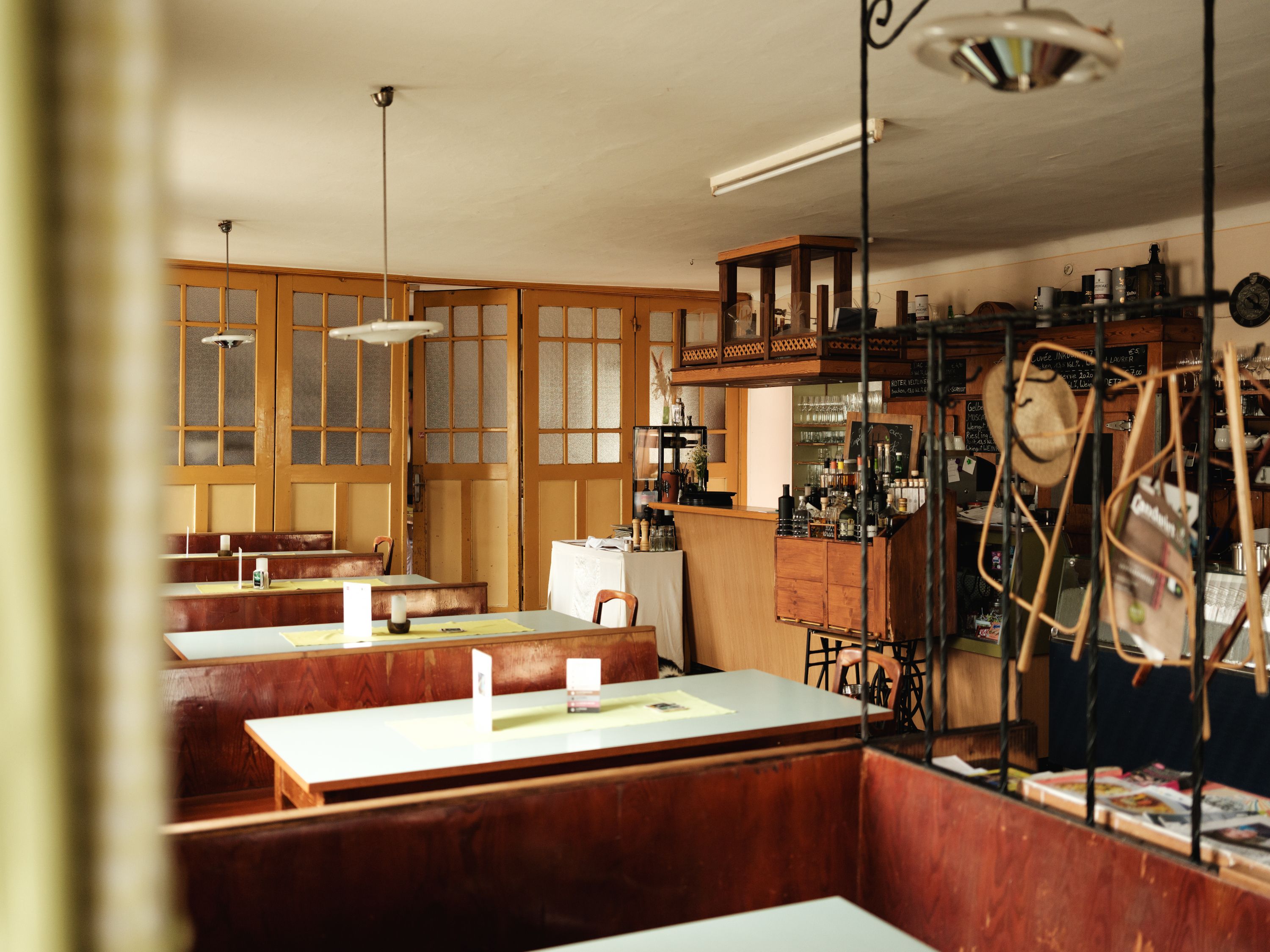 Innenansicht eines traditionellen Gasthauses mit Holztischen und Bar.