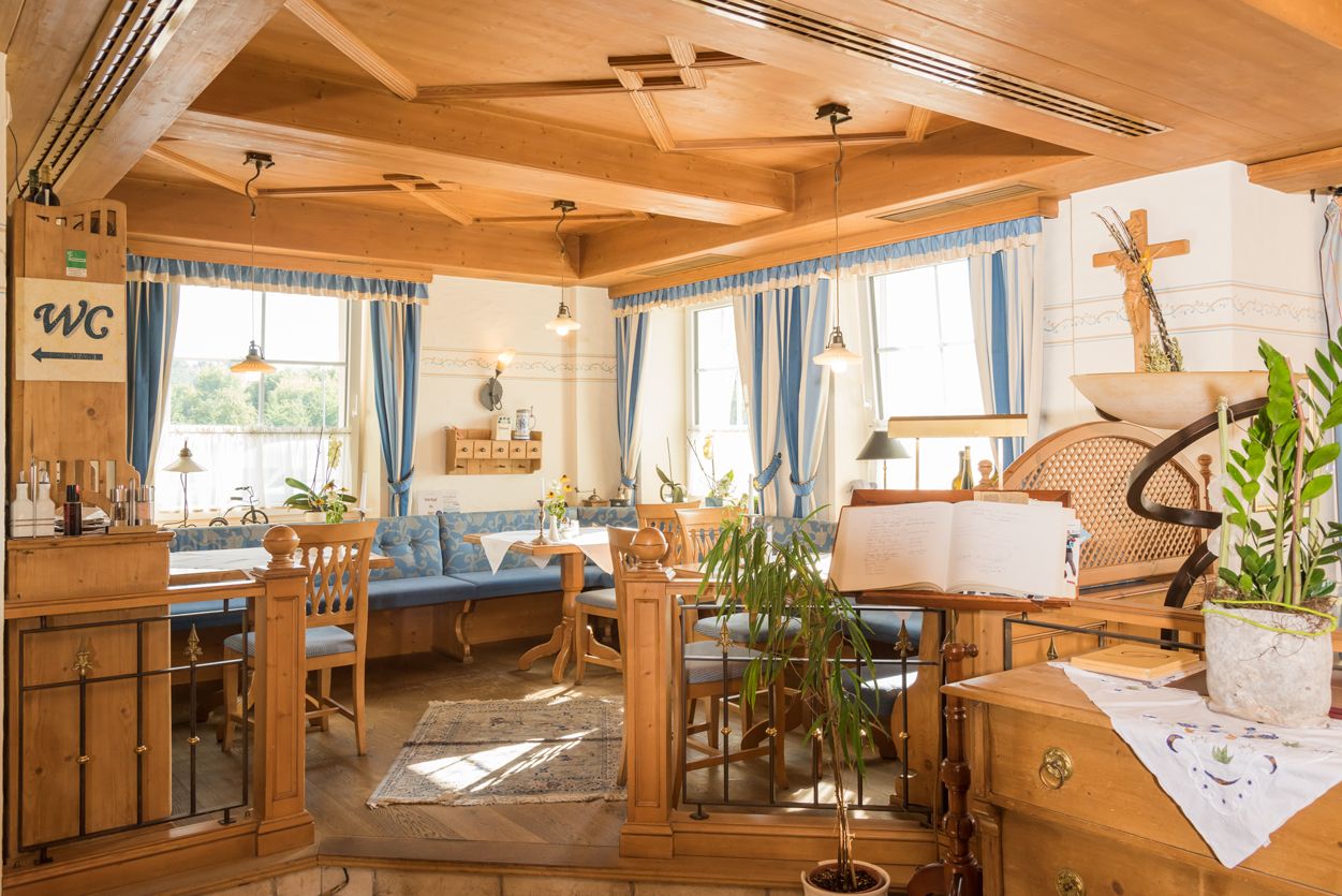 Gemütlicher Restaurantbereich mit Holzmöbeln und blauen Vorhängen.