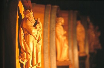 Holzskulpturen in warmem Licht, die in einer Reihe angeordnet sind.