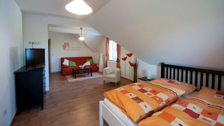 Gästezimmer, © Familie Rain Gemütliches Gästezimmer mit Doppelbett, Sofa, Fernseher und dekorativen Elementen.