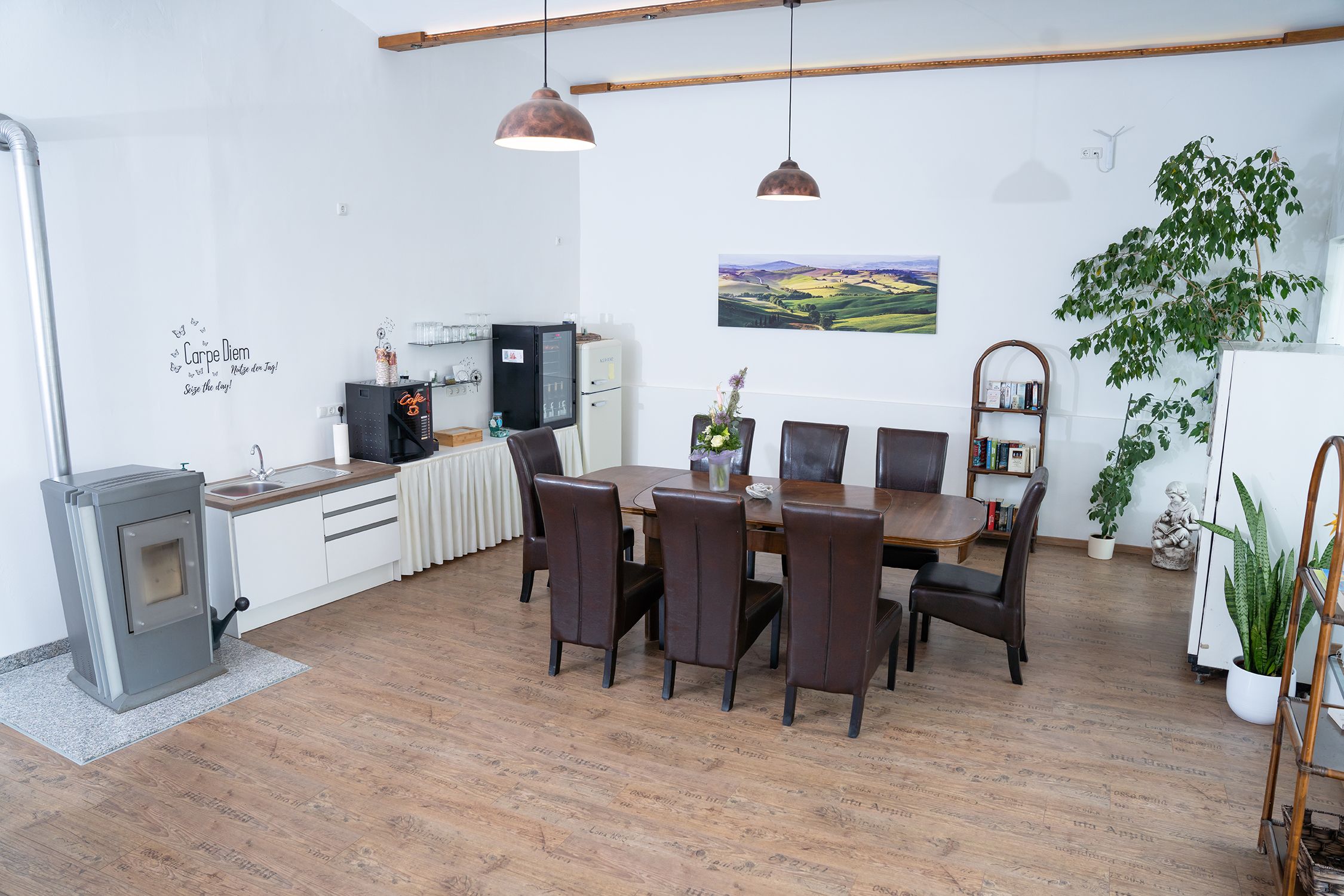 Gemütlicher Raum mit Esstisch, Stühlen, Pflanzen und Küchenzeile.