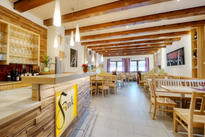 Innenansicht eines gemütlichen Gastraums mit Holzmöbeln und Theke im Heurigenstil.