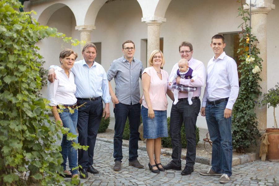 Eine Familie steht draußen vor einem Gebäude mit Bögen, umgeben von Pflanzen.
