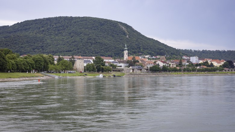 Blick auf Hainburg/Donau am Flussufer mit H&uuml;gel im Hintergrund.