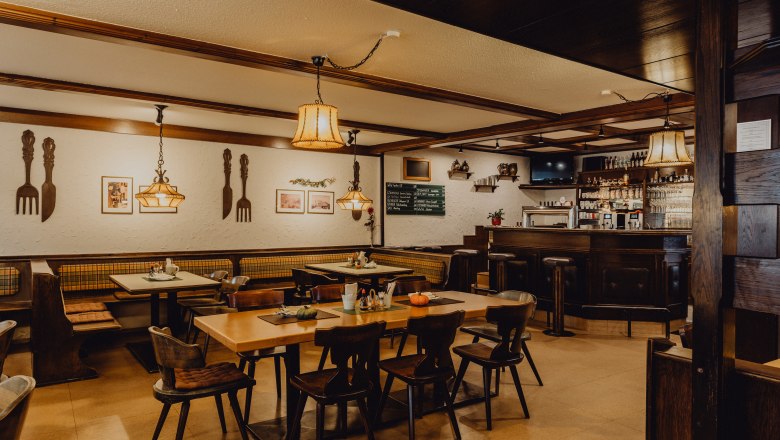 Gem&uuml;tliches Wirtshaus mit Holzm&ouml;beln, Bar und dekorativen Lampen.