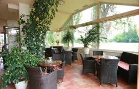 Ein gem&uuml;tlicher Wintergarten mit Korbm&ouml;beln und Pflanzen.