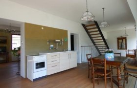 Innenansicht eines Wohnraums mit Küche, Esstisch und Treppe.