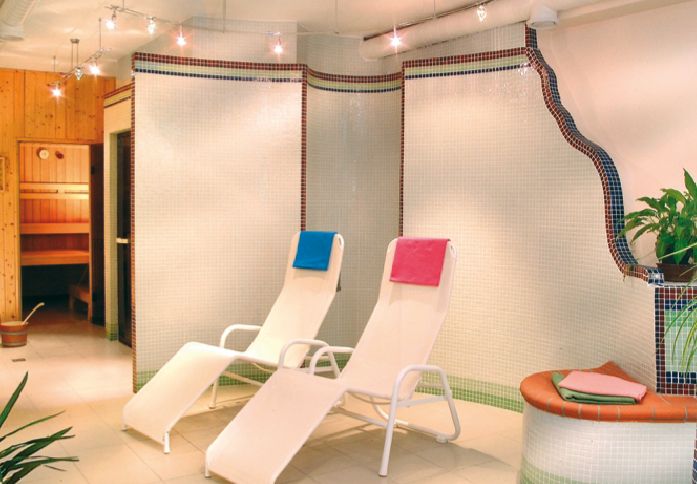 Wellnessbereich mit zwei Liegestühlen und Sauna.