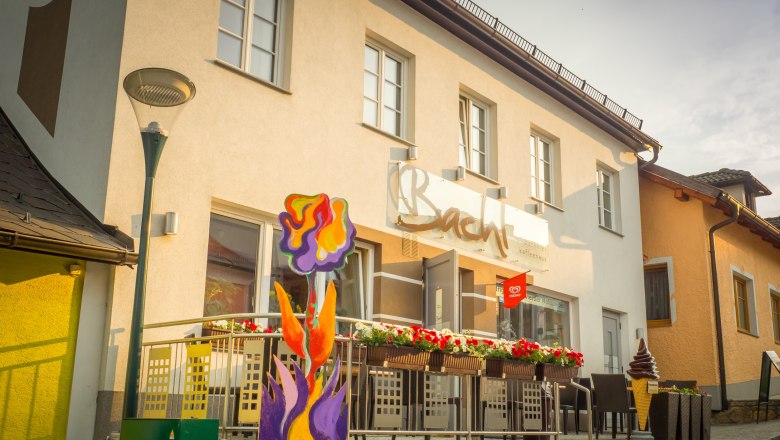 Au&szlig;enansicht eines Caf&eacute;s mit Terrasse und bunter Blumendekoration.