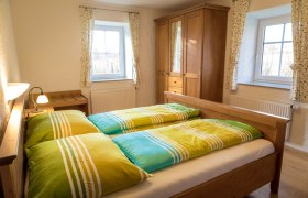 Gemütliches Schlafzimmer mit Holzmöbeln und bunten Bettbezügen.