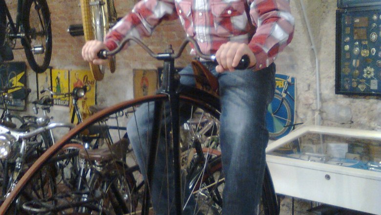 Ein Junge mit Hut sitzt auf einem Hochrad im Fahrradmuseum Schloss V&ouml;sendorf.