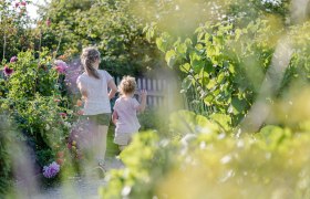 Zwei Kinder laufen durch einen blühenden Gartenweg.