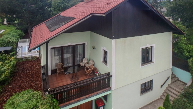 Das Hundeparadies im Pulkautal, © Novasol / Fam. Schachner Zweistöckiges Haus mit rotem Dach und Balkon, umgeben von Bäumen.