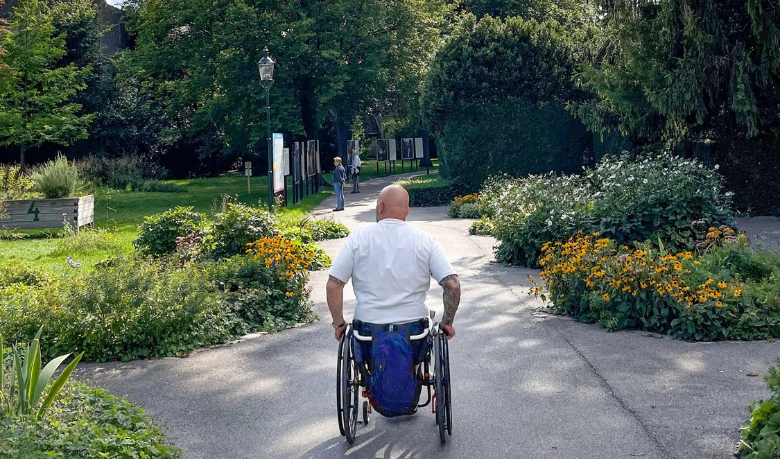 Ein Mann im Rollstuhl auf einem schönen Spazierweg in Baden bei Wien.