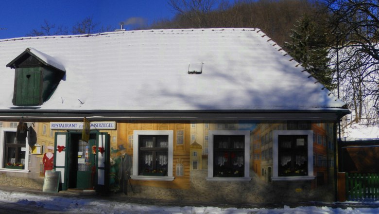 Ein verschneites Geb&auml;ude mit bemalter Fassade und der Aufschrift 'Restaurant Kaiserziegel'.