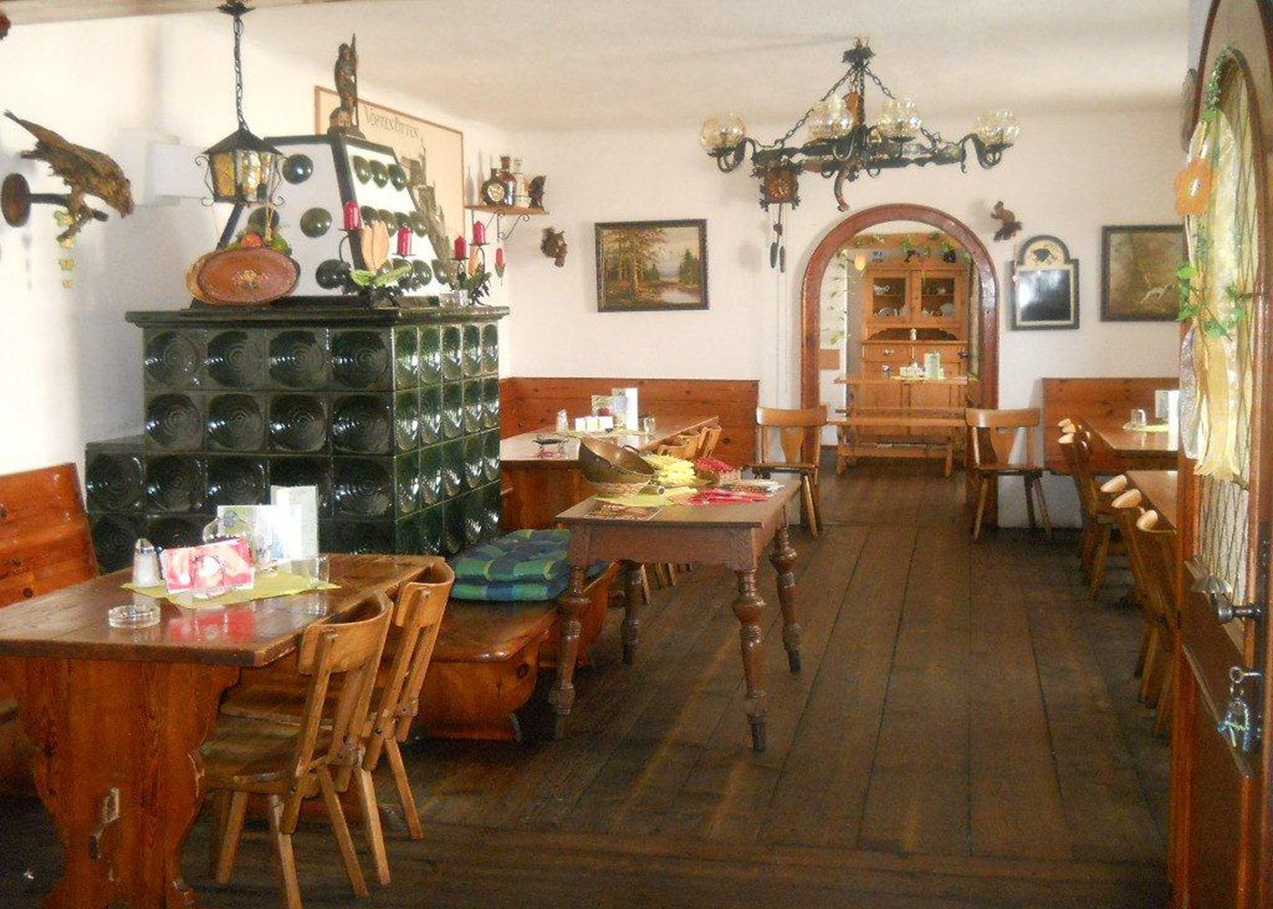 Innenansicht eines traditionellen österreichischen Heurigen mit Holzmöbeln und Kachelofen.