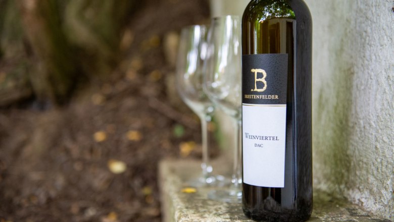 Weinflasche mit zwei leeren Gl&auml;sern im Freien.