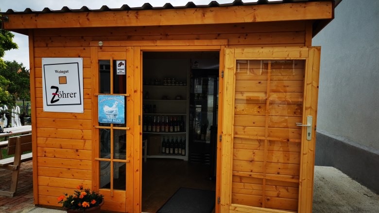 Kleines Holzgebäude mit Schildern des Weinguts Zöhrer und für frische Eier.