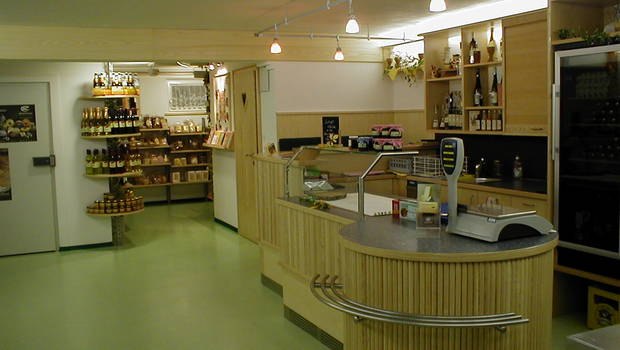 Innenansicht eines Imkereigesch&auml;fts mit Verkaufsbereich und Regalen voller Honigprodukte.