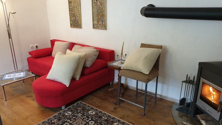 Gem&uuml;tliche Wohnzimmer-Ecke mit rotem Sofa, Kamin und Teppich.