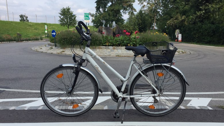 Fahrrad auf einer Stra&szlig;e vor einem Kreisverkehr in Tulln, umgeben von Blumen und B&auml;umen.