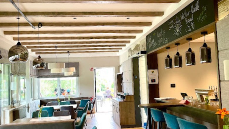 Restaurantbereich innen mit Tischen und grünen Sesseln