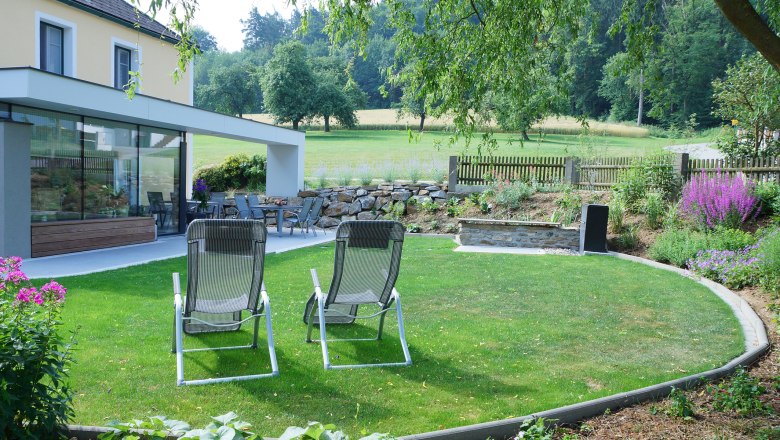 Garten auf der Lugerfarm, © Lugerfarm Garten mit Liegestühlen, Terrasse und Pflanzen auf der Lugerfarm.