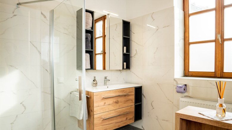 Modernes Badezimmer mit Holzmöbeln, großer Fensterfront und Glasdusche.