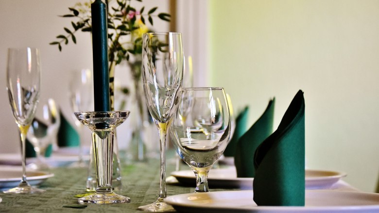 Eleganter Tisch mit Weingläsern, Kerze und gefalteten Servietten.