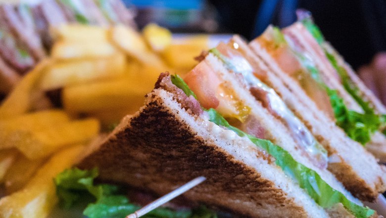 Nahaufnahme von Club Sandwiches mit Pommes Frites im Hintergrund.