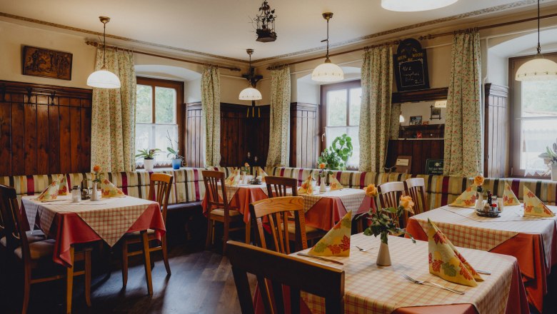 Gem&uuml;tliches Gasthaus mit Holzm&ouml;beln und karierten Tischdecken.
