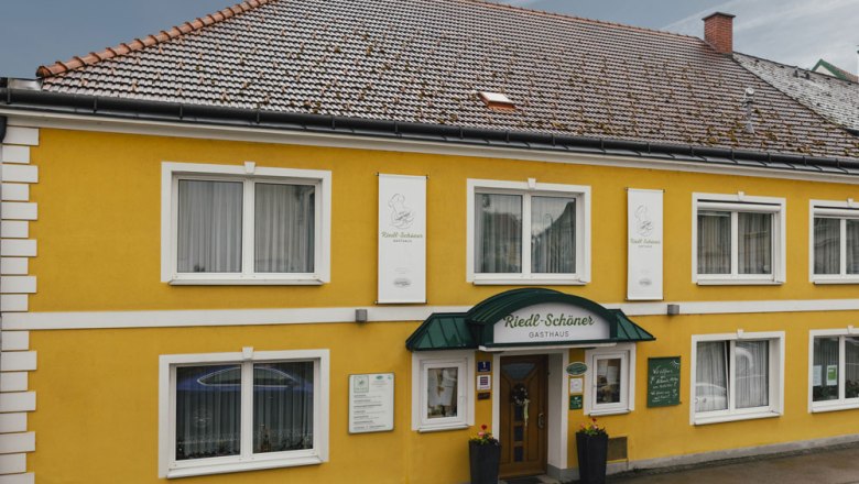 Gelbes Gasthaus mit gr&uuml;ner Markise und mehreren Fenstern.