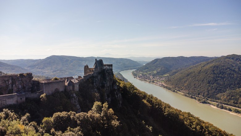 Luftaufnahme der Burgruine Aggstein mit Blick auf die Donau und umliegende Hügel.